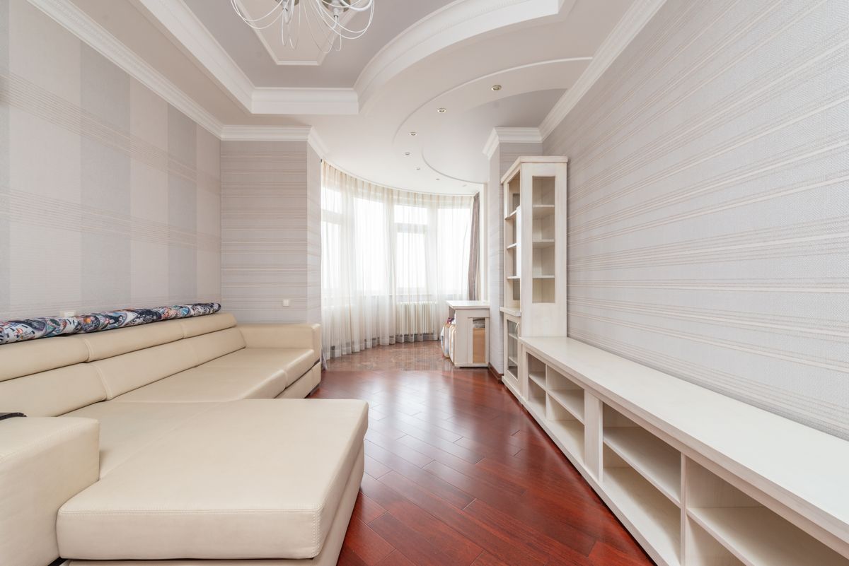 Long living room with a smooth white multi-level ceiling, recessed lighting, and a chandelier